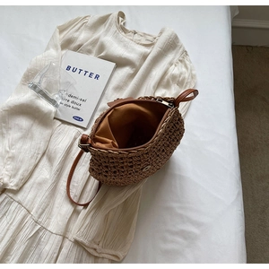 Detailed view of the woven straw crossbody bag featuring a secure zipper and magnetic closure