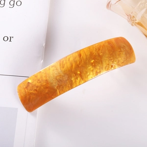 Close-up of golden amber acetate hair clip with checkered texture on a book background
