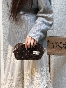 Gros plan sur une trousse en peluche marron à pois blancs tenue dans un cadre chic