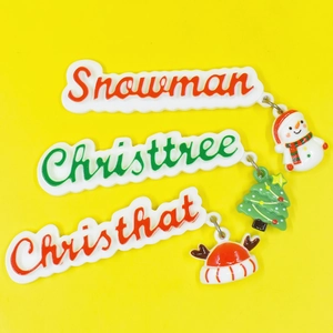 Detailed view of resin Christmas charms featuring Snowman and Xmas tree on yellow background
