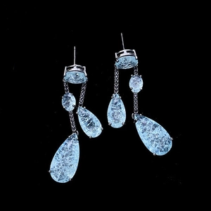 Macro view of light blue teardrop earrings with silver finish and intricate ice-crack texture
