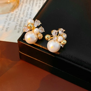 Close-up of gold-plated flower earrings with white pearls and sparkling cubic zirconia