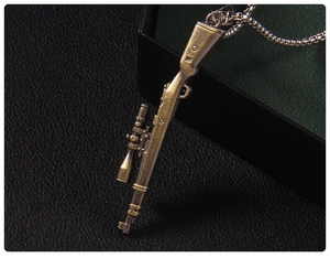 Close-up of vintage bronze submachine gun pendant with scope on a metal chain
