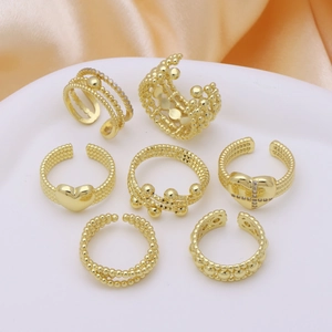 7-piece gold adjustable ring set with heart and cross motifs on peach silk background
