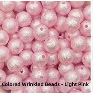 Detailed view of light pink textured round beads with wrinkled surface for DIY jewelry making