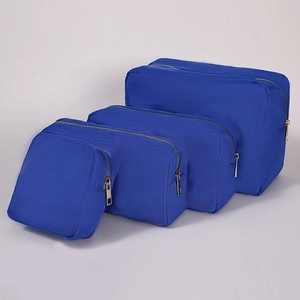 Detail view of four blue nylon waterproof cosmetic bags in various sizes with gold zippers