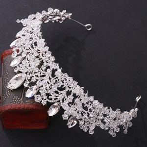 Close-up of a silver bridal crown with intricate crystals resting on a vintage wooden box