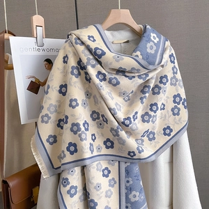 Detail of vintage floral knit shawl with fringes draped on coat and wooden hanger