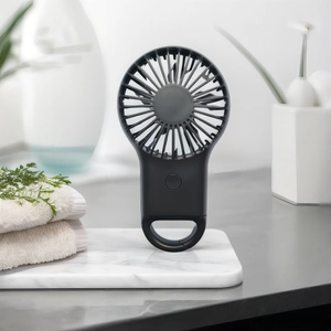 Macro shot of portable black mini fan on white marble base with built-in ring hook