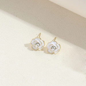 Macro shot of white camellia stud earrings with gold edges and diamond-like centers