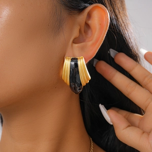 Detail of vintage-style fan-shaped gold earrings with black enamel for women