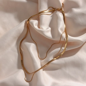 Detail of 18K gold plated triple layered herringbone snake chain necklace with lobster clasp