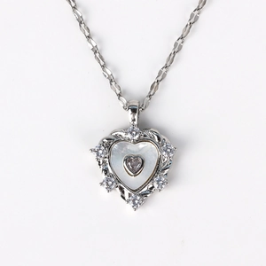 Detailed view of silver heart pendant with white stone and faceted metal chain necklace