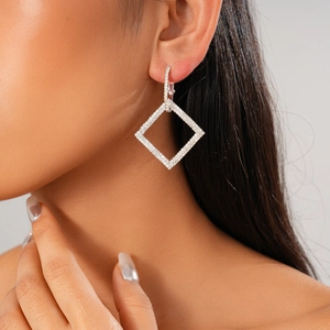 Close-up of elegant silver geometric diamond earrings worn by a model in profile