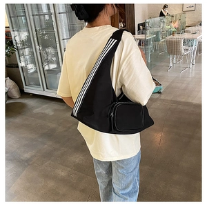 Detail of black nylon crossbody bag featuring three white stripes on the shoulder strap