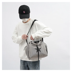 Macro view of grey crossbody bag with black star patch and drawstring closure details