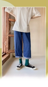 Detail of green ribbed mid-calf socks styled with denim jeans and canvas shoes
