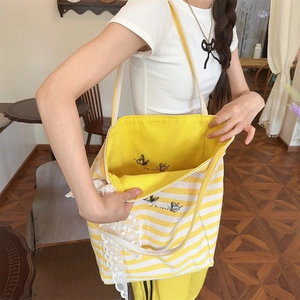 Detail of yellow striped canvas tote bag featuring delicate lace edges and butterfly embroidery