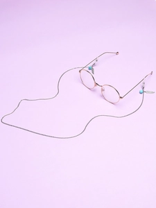 Detail of rose gold round glasses with silver chain featuring turquoise beads and feather pendant