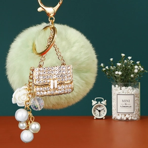 Close-up of pearl handbag keychain with mint green pompom and sparkling crystal charms