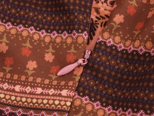 Détail d'une fermeture éclair rose invisible sur tissu à motif ethnique et texture tissée