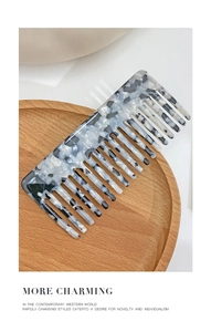 Macro view of wide-tooth acetate hair comb with tortoiseshell pattern on wood tray