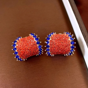 Detailed close-up of vintage C-shaped earrings with orange and blue rhinestones