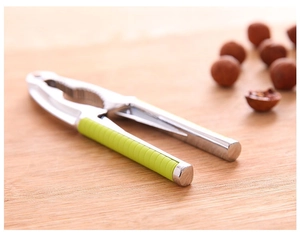 Macro shot of multifunctional nutcracker with green handles on a wooden cutting board