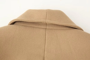 Close-up detail of the double-layered lapel and fine stitching on camel wool coat