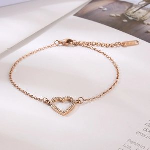 Détail d'un bracelet cœur en or rose avec cristaux micro-pave sur une page de livre