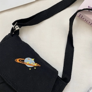 Close-up of black canvas bag featuring colorful planet embroidery and adjustable strap
