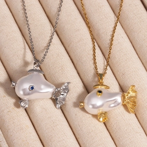 Close-up of pearl fish necklaces in silver and gold finish with blue gemstone eyes