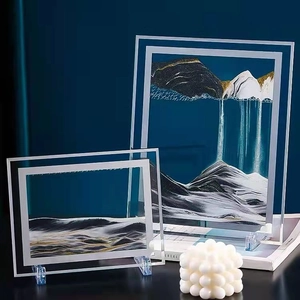 Modern hourglass moving sand art with gold and black liquid flows in 3D glass frames
