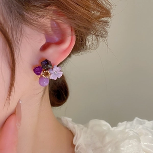 Close-up of elegant purple floral earrings featuring resin petals and crystal accents