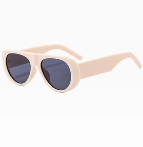 Detail view of cream oversized sunglasses with thick retro frames and dark resin lenses