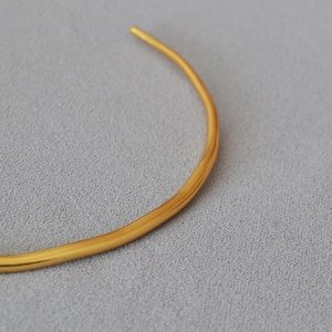 Macro view of gold plated irregular minimalist necklace choker with metallic texture