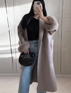 Detail of long taupe wool coat with faux fur cuffs and collar in a mirror selfie view