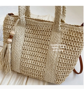 Detail of straw woven tote bag featuring tassel charms, wooden beads and leather strap