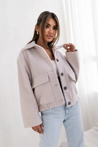 Gros plan sur la veste en laine gris clair avec grandes poches et détails de boutons