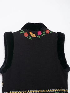 Detailansicht der schwarzen Strickweste mit bunter Blumenstickerei und Kunstpelzbesatz