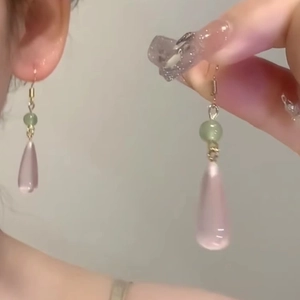 Detail of tear-drop resin earrings with pale green bead and light pink stone pendant