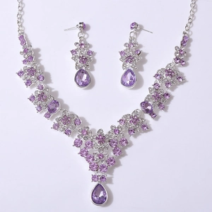 Detail of bridal jewelry set with purple crystals, V-shaped floral necklace and earrings