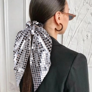 Detail of silver sequined scrunchie with bow ribbon worn on high ponytail style