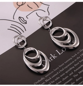 Detail of silver geometric triple oval hoop earrings on artistic prop background