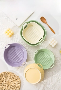 Close-up of colorful ceramic baking bowls with double handles on lace tablecloth