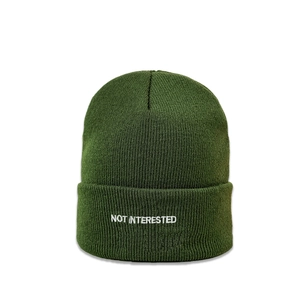 Detailed view of white NOT INTERESTED embroidery on dark green knitted beanie cap