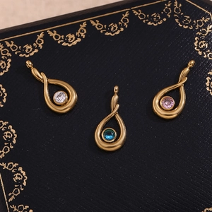 Detailed view of three 18K gold teardrop pendants with white, blue, and pink zircon stones