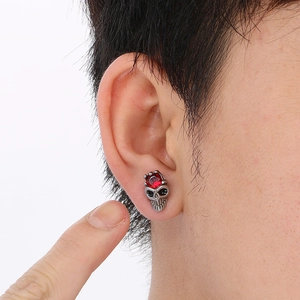 Detailed view of skull stud earring with a red gemstone in punk style worn on ear