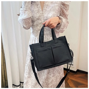 Detail of black pebbled PU leather tote with dual front pockets and adjustable strap