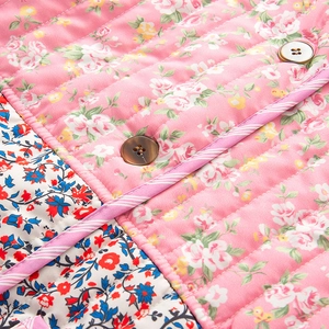 Détail de la veste matelassée à fleurs roses avec boutons bruns et couture précise